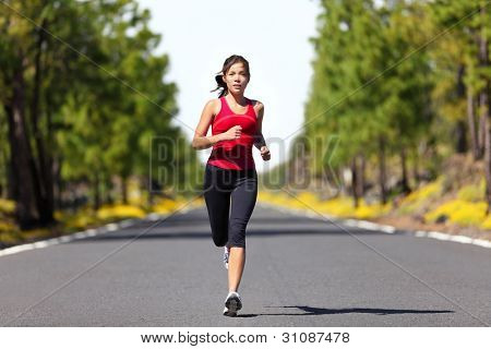 Picture or Photo of Sport fitness running woman jogging during outdoor workout. Beautiful young female athlete runner training for marathon on forest road in spring or summer. Mixed race Asian woman fitness model.