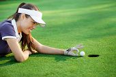 foto of golf  - female golfer flick the golf ball into the hole - JPG 