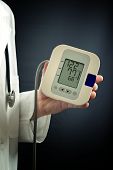 image of pressure  - Male doctor holding a digital blood pressure meter device in his left hand - JPG 