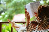 foto of woman  - Young woman reading a book lying in a hammock - JPG 