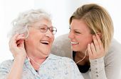 pic of home  - Excited grandmother listening music together with her granddaughter at home - JPG 