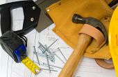 picture of construction worker  - Items used by a construction worker including a leather tool belt a hammer a tape measure tools floor plans and a yellow hard hat - JPG 