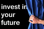stock photo of investment  - invest in your future concept with blue curtain hand and black background - JPG 