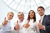 stock photo of business people  - Portrait of four successful business people showing thumbs up and looking at camera - JPG 
