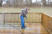 stock photo of pressure  - Worker pressure washing deck on rear of house - JPG 