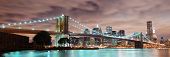 stock photo of buildings  - New York City Manhattan panorama view with Brooklyn Bridge at night with office building skyscrapers skyline illuminated over Hudson Rive - JPG 