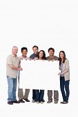 stock photo of group  - Smiling group of friends holding blank sign together against a white background - JPG 