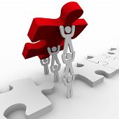 picture of puzzle  - A team works together to lower the final puzzle piece - JPG 