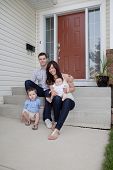 image of family  - Portrait Of Sweet Family Sitting In Front Of Their House - JPG 