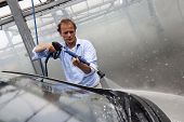 image of pressure  - Man washing the windscreen of his car in a cubicle with a high pressure water jet - JPG 