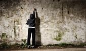 stock photo of youngster  - Youngster with spray paint and an empty wall for graffiti - JPG 