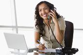 stock photo of business people  - Businesswoman in office on telephone by laptop smiling  - JPG 