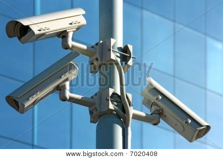 Picture or Photo of Three security cameras on electricity tower and glass facade