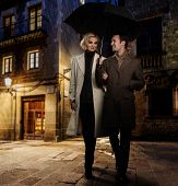 pic of outdoor  - Elegant couple in autumnal coats walking in the rain outdoors at night - JPG 