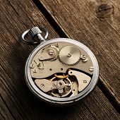 image of watch  - Clockwork mechanism over wooden background - JPG 
