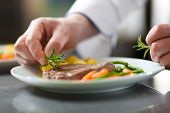 stock photo of restaurant  - Chef decorating a dish in restaurant kitchen - JPG 