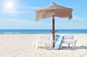 stock photo of beach  - Wooden beach umbrella and sun bed on the beach in the background the blue sea - JPG 