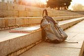 pic of objects  - Old denim school backpack with copybooks left on the stone steps - JPG 