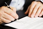 image of sign  - Businessman sitting at office desk signing a contract with shallow focus on signature - JPG 