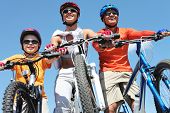 stock photo of blue  - Portrait of happy family on bicycles against blue sky - JPG 