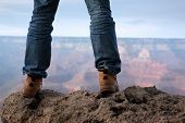 image of standing  - Man in hiking boots standing on edge of a cliff in Grand Canyon Arizona - JPG 