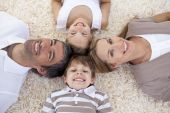 stock photo of family  - Smiling family lying on floor with heads together - JPG 