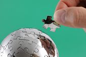 picture of puzzle  - Hand holding puzzle piece completing global puzzle - JPG 