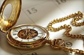picture of watch  - Close up of a gold pocket watch on a calendar in sunlight - JPG 