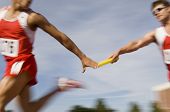 picture of pass  - Blurred motion male runners passing baton in relay race - JPG 