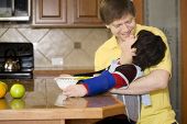 stock photo of cerebral  - Father helping disabled son putting fruit into bowl in the kitchen - JPG 