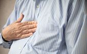 picture of businessmen  - businessman indicates where he feels discomfort from heartburn - JPG 