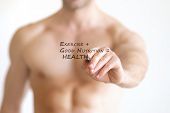 stock photo of health  - Concept photo of a fit young shirtless man writing the formula for good health on transparent board that reads  - JPG 