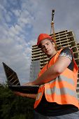 image of construction worker  - Construction supervisor in safety helmet and reflex vest with notebook in front of construction site - JPG 