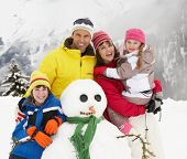 picture of holidays  - Family Building Snowman On Ski Holiday In Mountains - JPG 
