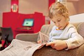 stock photo of newspaper  - Little girl sitting in chair in cabin big passenger ship read newspaper - JPG 
