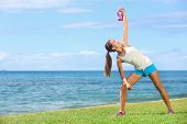 image of fitness  - exercise woman using kettlebell in fitness strength training workout outside on grass by the ocean - JPG 