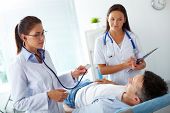 foto of medical doctors  - Portrait of two female doctors looking at patient during medical treatment in hospital - JPG 