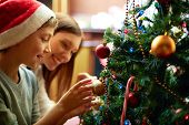 picture of boy  - Portrait of happy boy in Santa cap decorating Christmas tree - JPG 