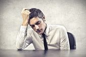 pic of businessmen  - Desperate young businessman leaning on a desk - JPG 