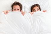 pic of wake  - Funny couple in bed looking and peeking over sheets surprised - JPG 