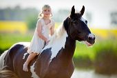 stock photo of horse  - Child riding a horse in meadow in spring - JPG 