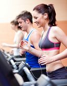 foto of fitness  - Beautiful female athlete standing on a running machine listening to the music in a fitness centre - JPG 
