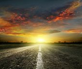 foto of sunset  - Long country road with white lines down the centre stretching off past a lone tree to the distant horizon - JPG 