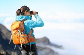 stock photo of watch  - Hiker looking in binoculars enjoying spectacular view on mountain top above the clouds - JPG 
