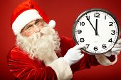 foto of minute  - Photo of Santa pointing at clock showing five minutes to midnight - JPG 
