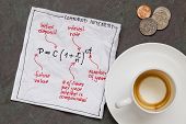 stock photo of interest  - compound interest equation on a cocktail napkin with empty coffee cup and coins on a slate stone table - JPG 
