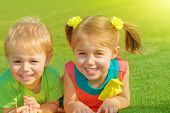 foto of outdoor  - Photo of little brother and sister lying down on green grass field in sunny day - JPG 