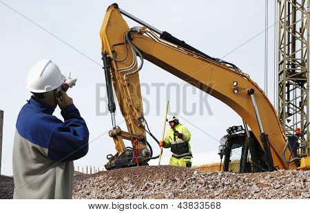 Picture or Photo of Bulldozer and industrial workers in action, inside building site