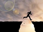 picture of gap  - Concept or conceptual young man or businessman silhouette jump happy from cliff over  gap sunset or sunrise sky background - JPG 