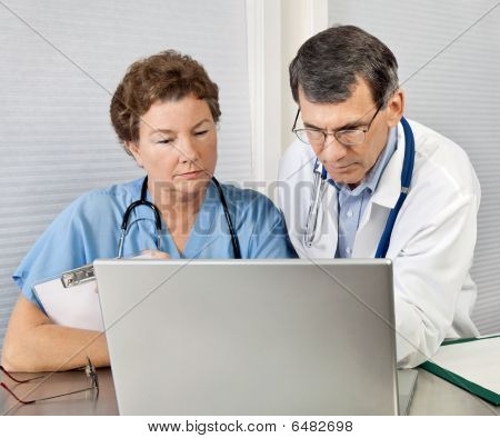 Picture or Photo of Doctor And Nurse Talking and Working at Laptop Computer In Office